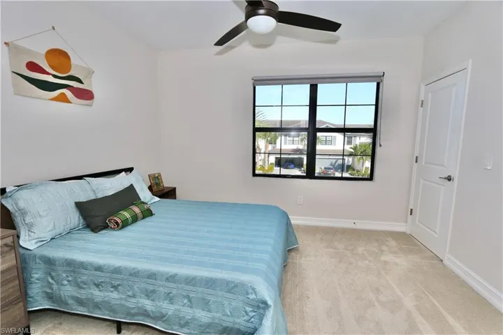 Bedroom with light colored carpet and a ceiling fan