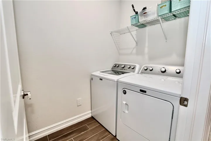 Laundry area featuring wood finish floors and washing machine and clothes dryer
