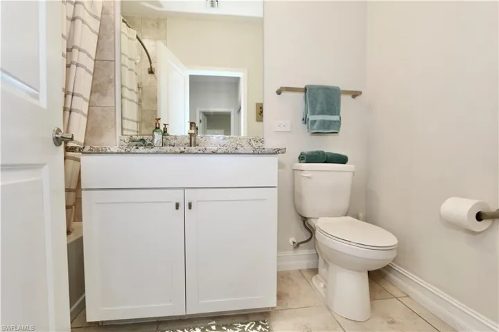 Full bathroom featuring curtained shower, vanity, and light tile patterned floors