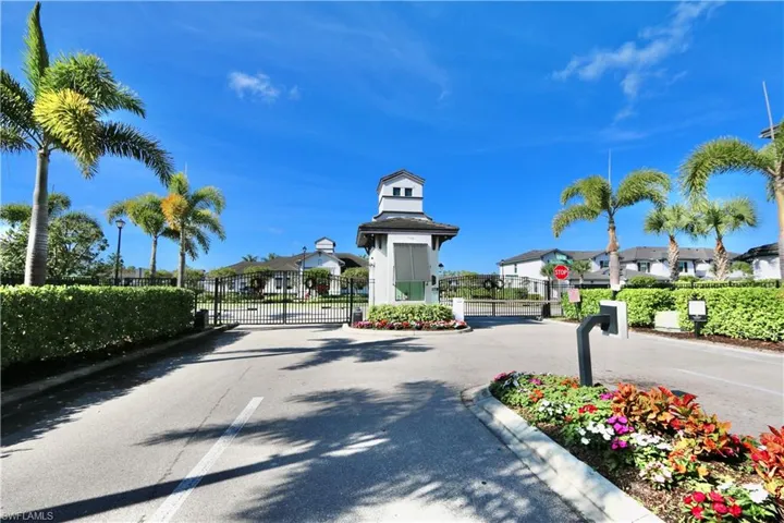 View of asphalt street with a gate, traffic signs, curbs, and a gated entry