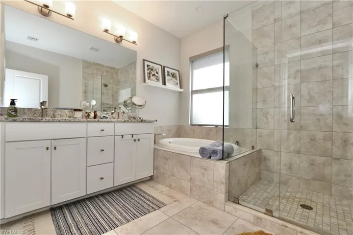 Full bath with double vanity, a shower stall, light tile patterned flooring, and a bath