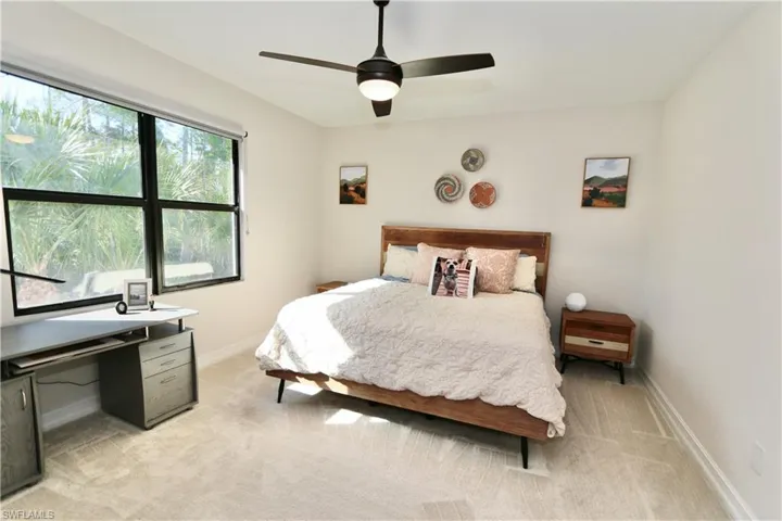 Bedroom featuring light colored carpet, ceiling fan, and a desk