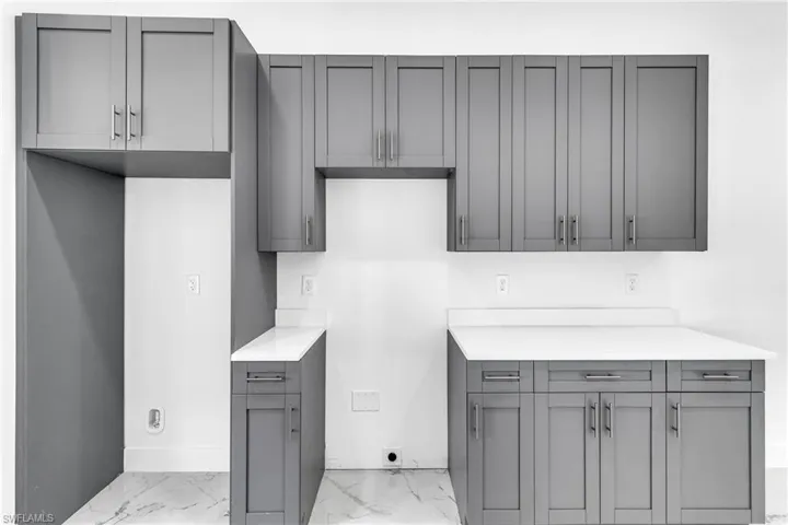Kitchen with light marble finish flooring, gray cabinets, and light stone countertops