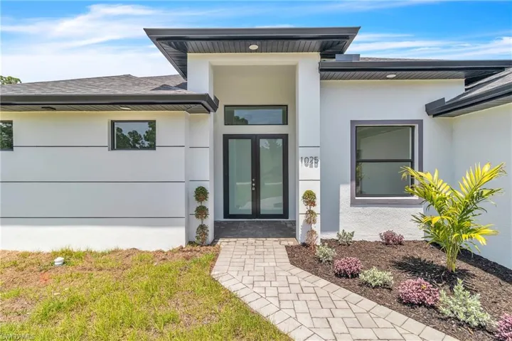 Property entrance featuring stucco siding, a lawn, roof with shingles, and french doors