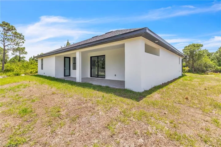 Rear view of property with a patio area, a yard, and stucco siding