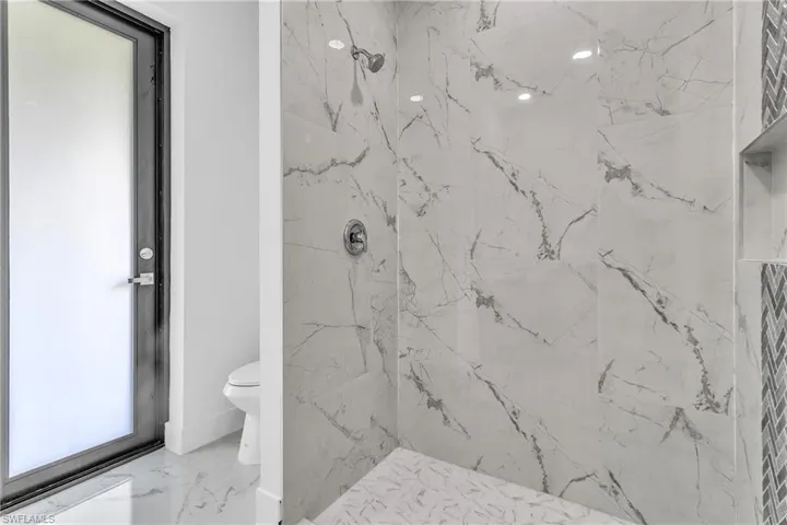Full bathroom featuring a marble finish shower and light marble finish floors