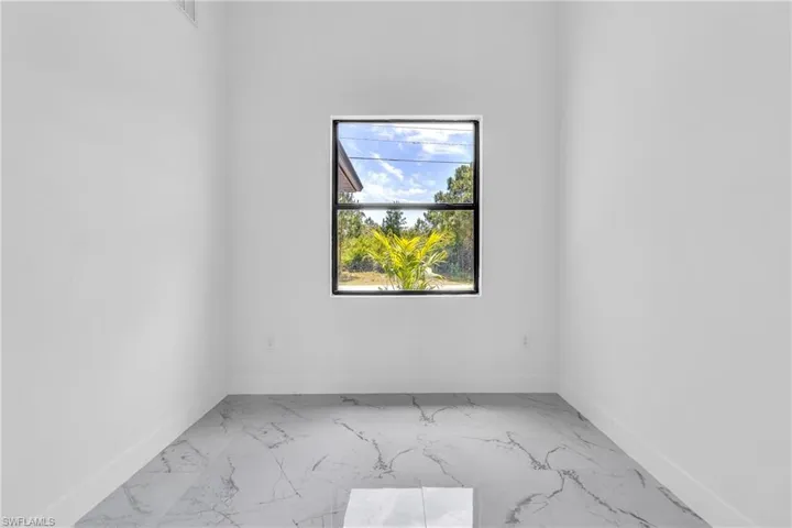 Spare room featuring marble finish floors and baseboards