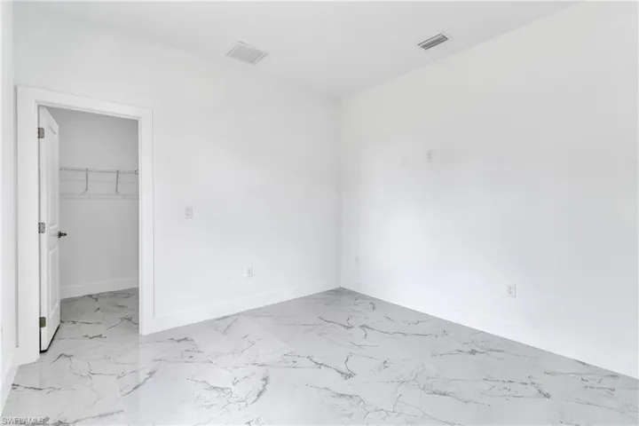 Unfurnished room featuring light marble finish floors and baseboards