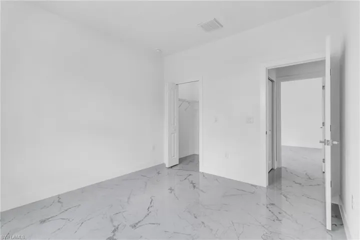 Unfurnished bedroom featuring a spacious closet and light marble finish flooring