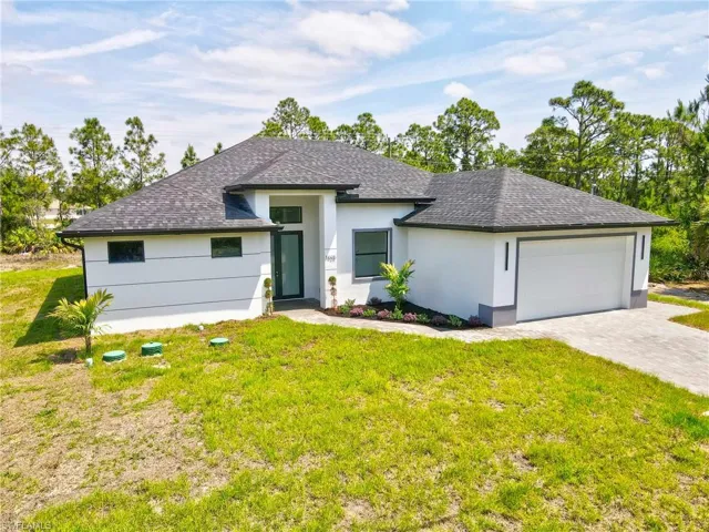 View of front of home with a front lawn, roof with shingles, and an attached garage