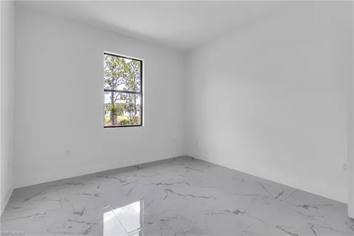 Unfurnished room featuring light marble finish flooring and baseboards