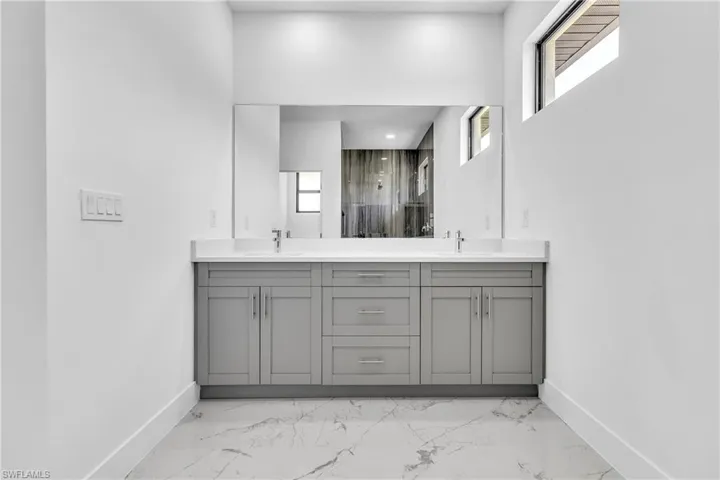 Full bath with a marble finish shower, double vanity, and light marble finish flooring