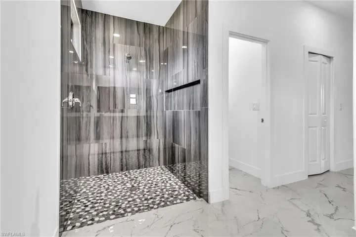 Bathroom with a tile shower and light marble finish flooring