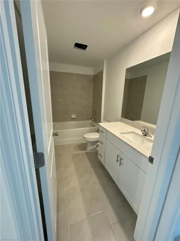 Bathroom featuring a white vanity with a stone countertop, an undermount sink, and a large wall-mounted mirror