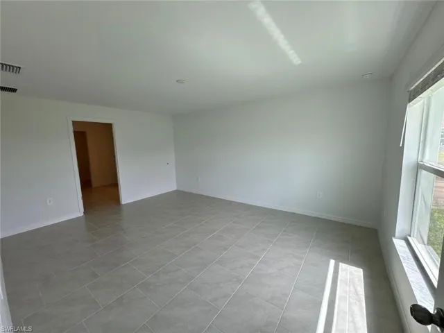 Spacious interior featuring neutral tone tile flooring, white painted walls, and recessed lighting