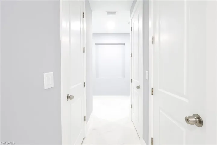 Hallway featuring light marble finish flooring and baseboards