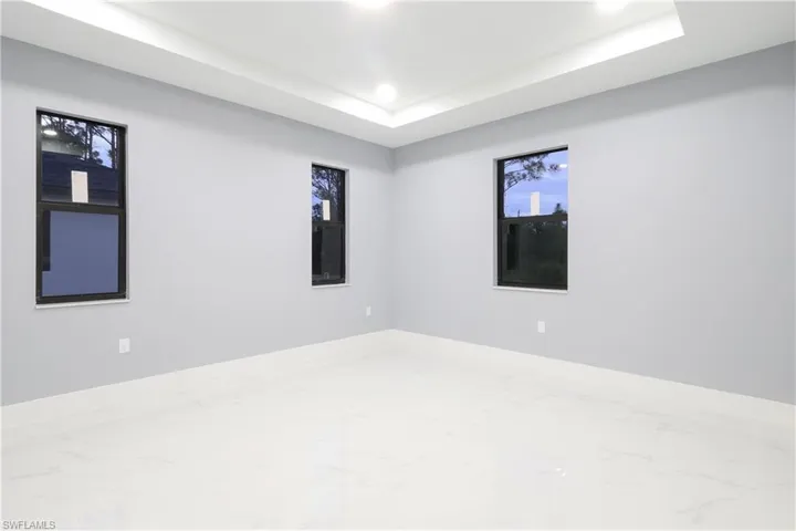 Spare room with a tray ceiling, marble look tiles, and recessed lighting