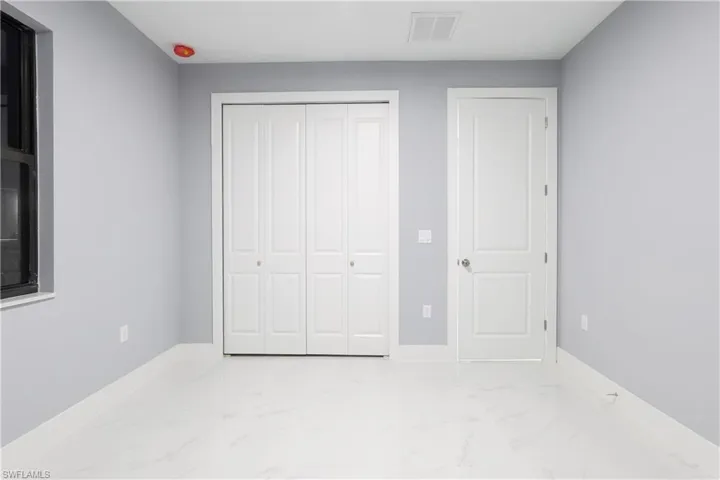 Unfurnished bedroom featuring light marble finish floors and a closet