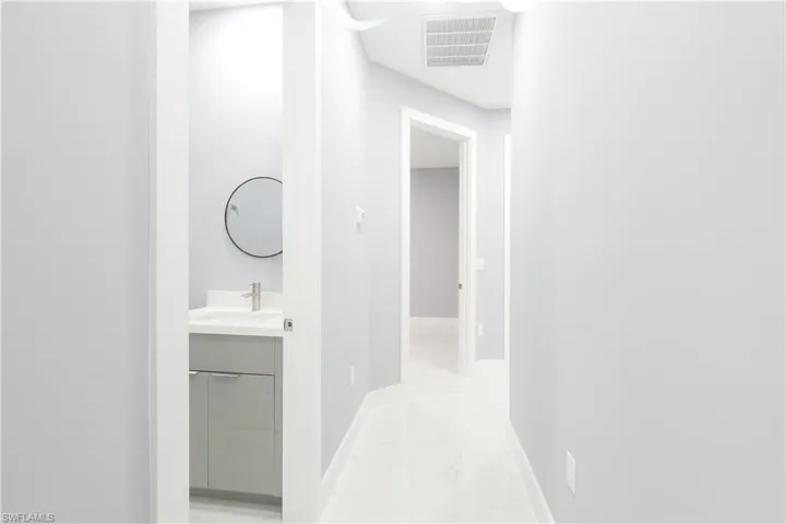 Corridor with light marble finish flooring and a sink