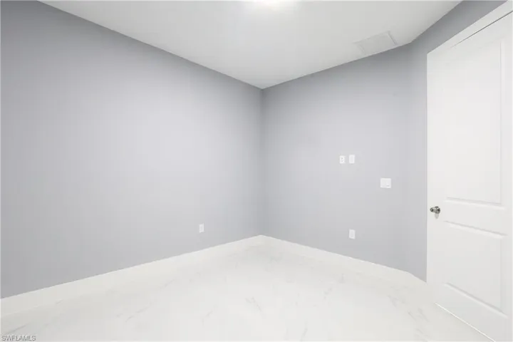 Empty room with marble look tiles and baseboards