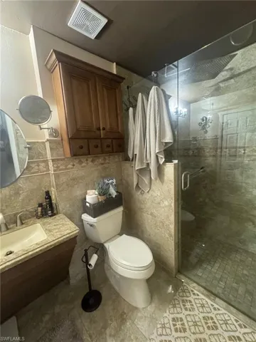 Bathroom featuring a stall shower, tile walls, vanity, and a wainscoted wall