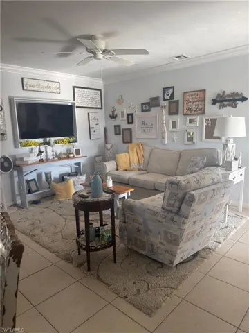 Living area featuring ornamental molding, light tile patterned floors, and a ceiling fan