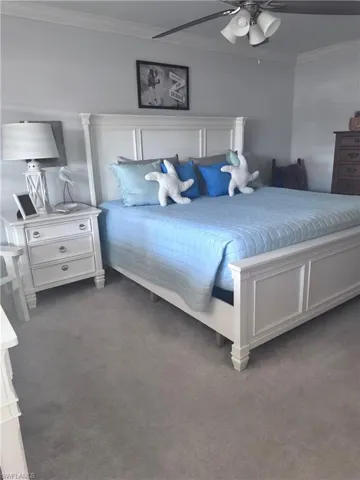 Carpeted bedroom with crown molding and ceiling fan