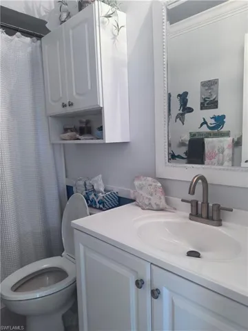 Full bath featuring curtained shower and vanity