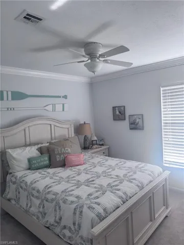 Carpeted bedroom featuring ornamental molding and ceiling fan