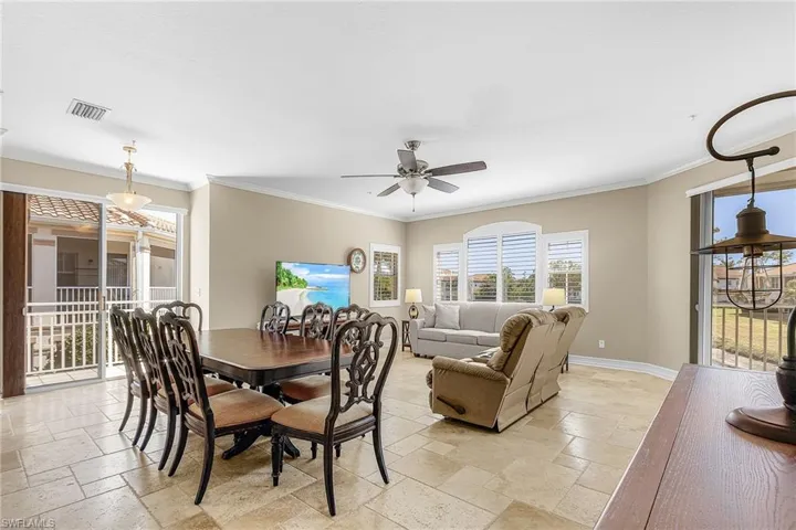 Dining space with stone tile floors, ceiling fan, and crown molding