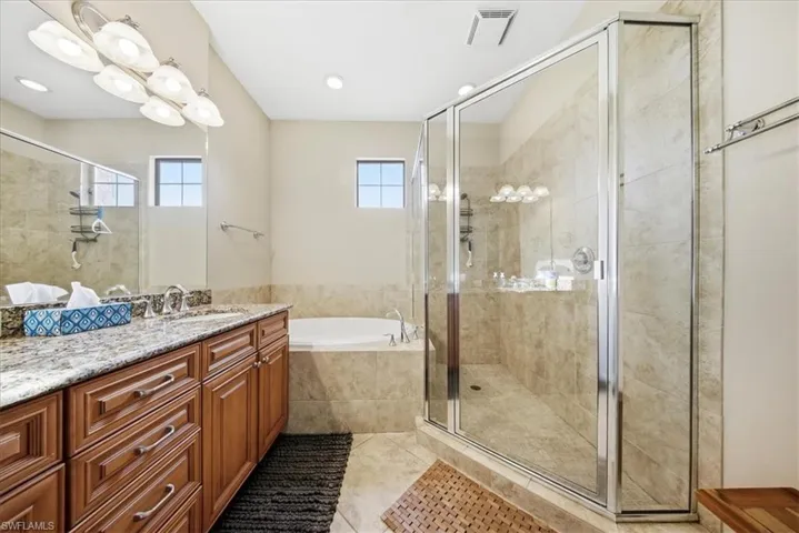 Bathroom featuring vanity, a bath, a stall shower, and light tile patterned floors