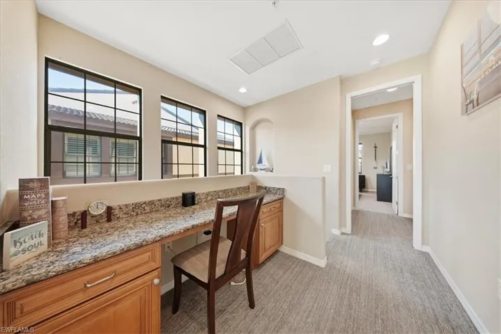 Office space with built in desk, light colored carpet, and recessed lighting