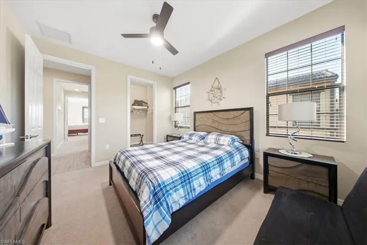 Bedroom with a spacious closet, light carpet, and ceiling fan