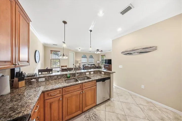 Kitchen featuring brown cabinetry, dark stone countertops, crown molding, and recessed lighting