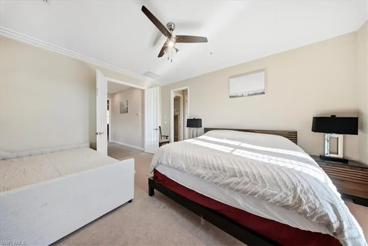 Carpeted bedroom featuring ornamental molding, a spacious closet, and ceiling fan