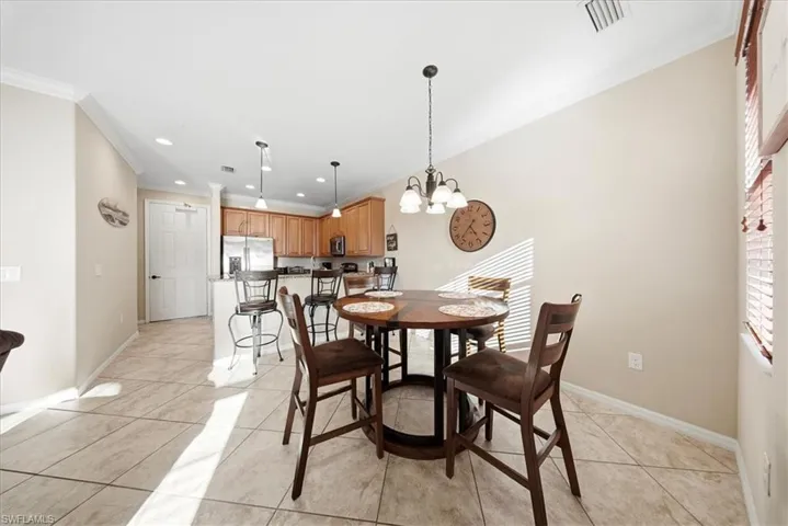 Dining area with ornamental molding, light tile patterned flooring, a chandelier, and recessed lighting