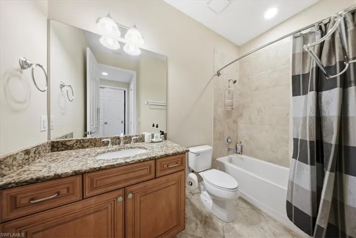 Bathroom featuring shower / bath combo with shower curtain, vanity, light tile patterned flooring, and recessed lighting