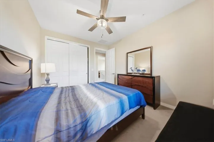 Carpeted bedroom with a ceiling fan and a closet