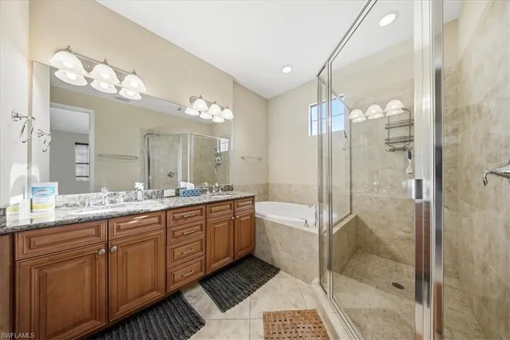 Full bathroom with double vanity, a shower stall, a bath, and light tile patterned flooring
