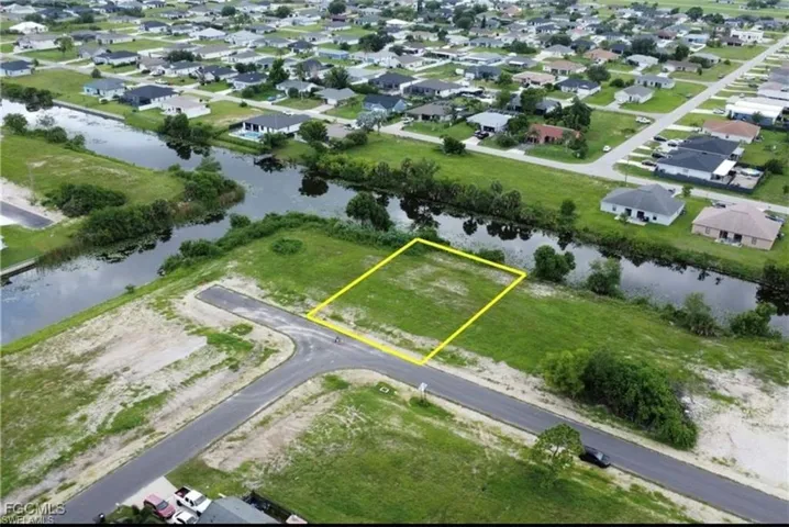 Aerial perspective of suburban area with property parcel outlined and a nearby body of water
