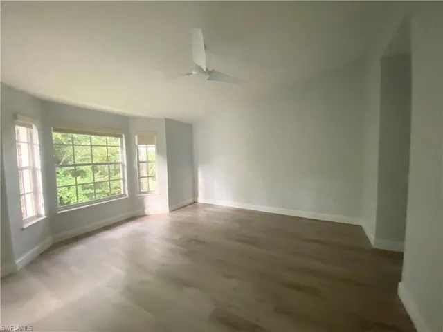 Master bedroom with preserve views, ceiling fan, a healthy amount of sunlight, lofted ceiling, and wood-type flooring