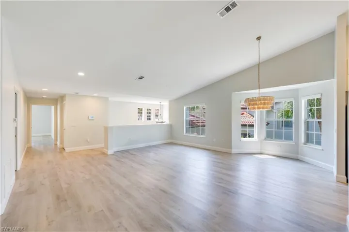 Unfurnished living room featuring vaulted ceiling and hardwood / wood-style flooring