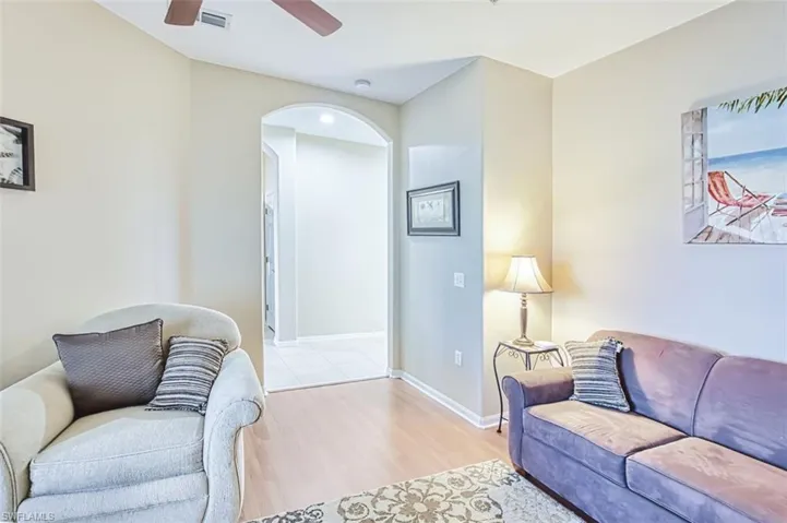 Living area with light wood finished floors, a ceiling fan, and arched walkways