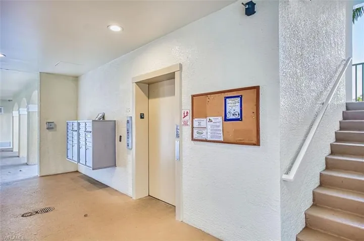 Hall featuring a textured wall, elevator, and concrete flooring