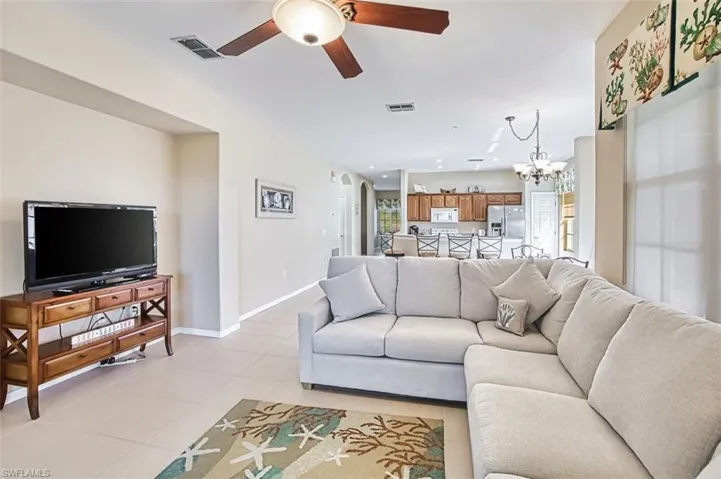Living area featuring arched walkways, a ceiling fan, a chandelier, and light tile patterned flooring