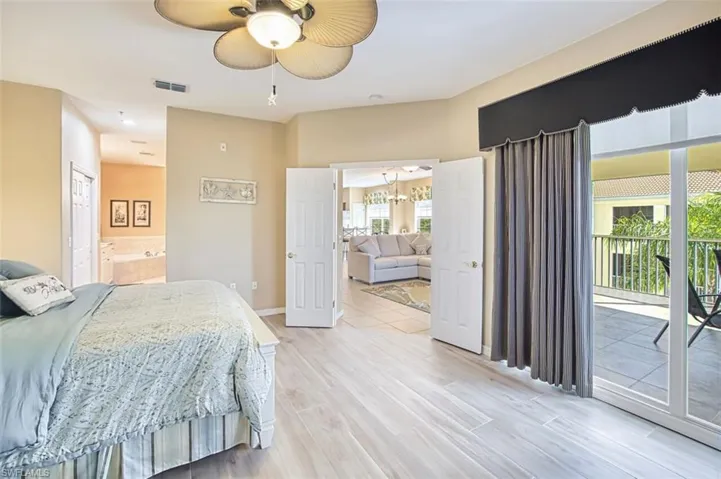 Bedroom with access to exterior, light wood-type flooring, ceiling fan, and ensuite bathroom