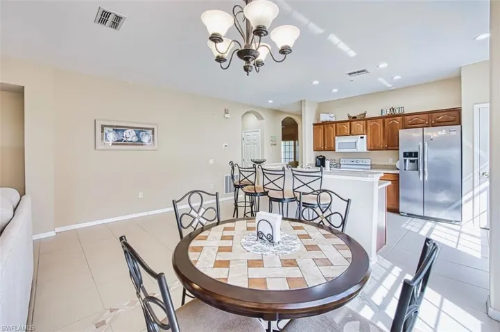 Dining room featuring light tile patterned floors, arched walkways, and hanging lights