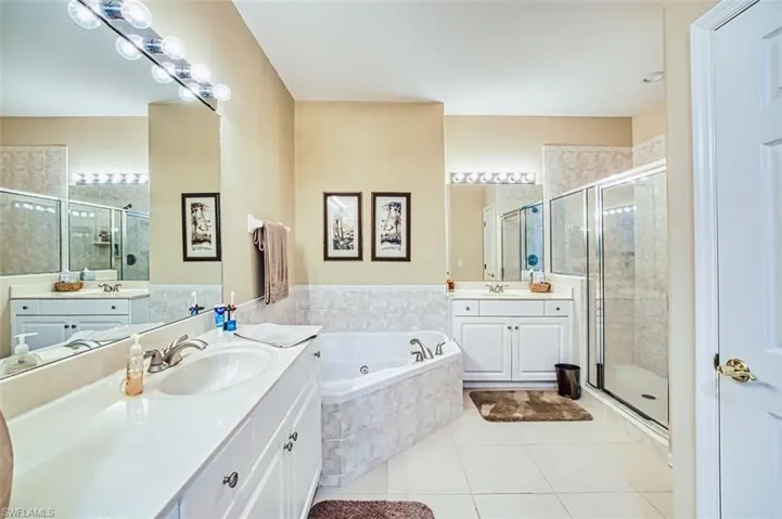 Bathroom with a shower stall, two vanities, a garden tub, and light tile patterned flooring
