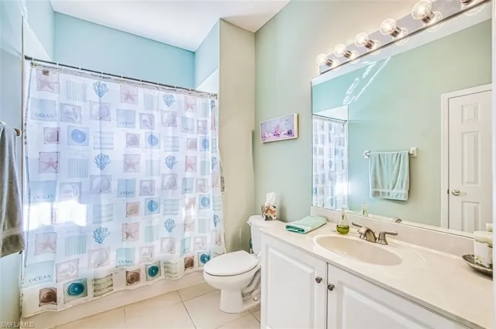 Full bathroom featuring vanity, a shower with shower curtain, and light tile patterned floors