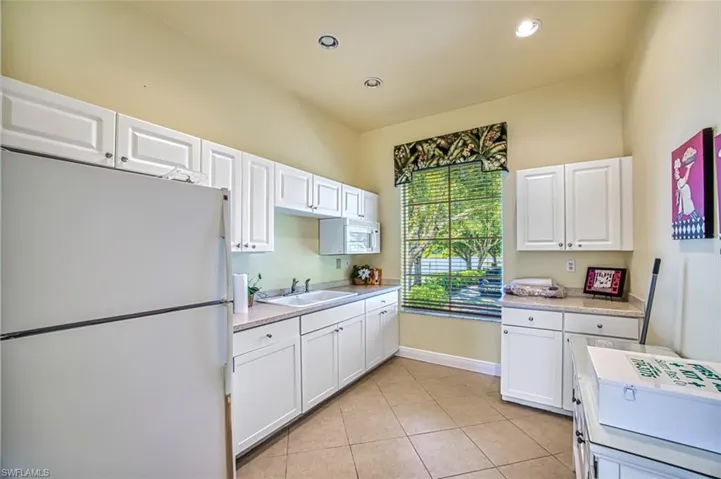 Kitchen with white appliances, light countertops, white cabinetry, light tile patterned floors, and recessed lighting